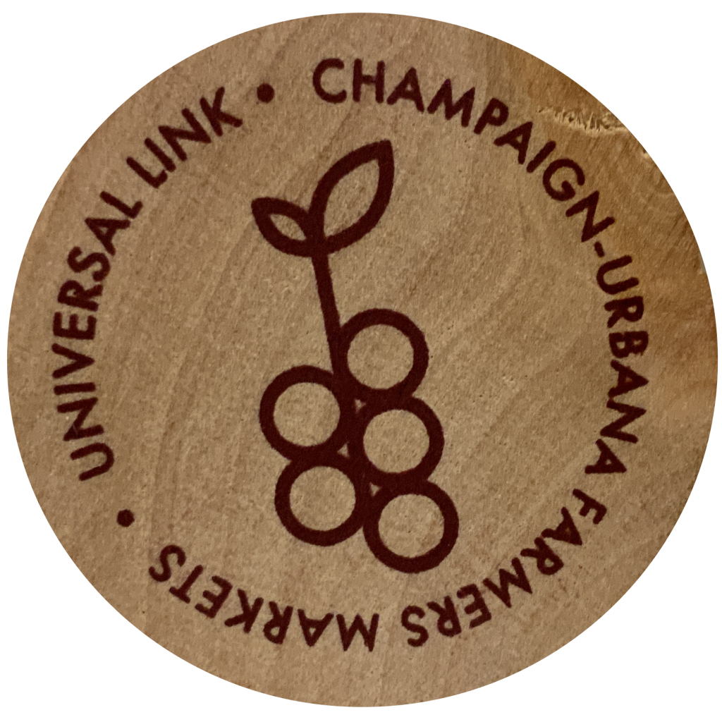 A wooden token stamped with an image of currants. Text reads: "Universal Link, Champaign-Urbana Farmers Markets"