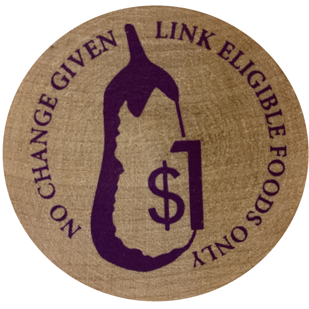 A wooden token stamped with an image of an eggplant. Text reads: "No change given, Link eligible foods only"
