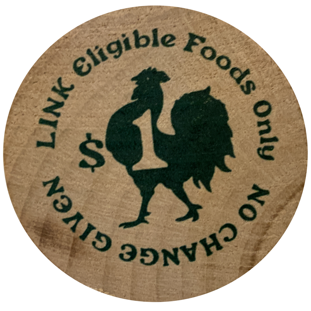 A wooden token stamped with an image of a rooster. Text reads: "No change given, Link eligible foods only"